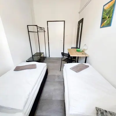 two beds in a room with a table and a mirror at Cute room D2 Prague 7 in Prague