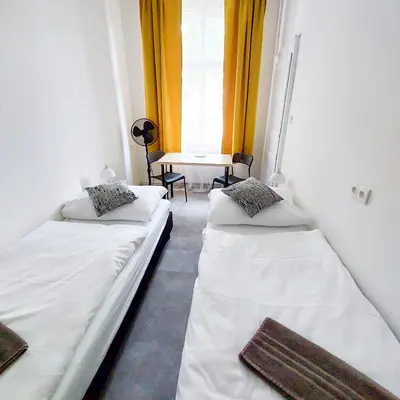 two beds in a room with a table and a window at Soukromý pokoj D5 u Výstaviště Holešovice in Prague