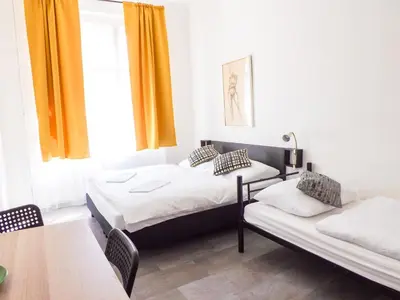a bedroom with two beds and a table and a window at Spacious room E1 in centre of Prague in Prague