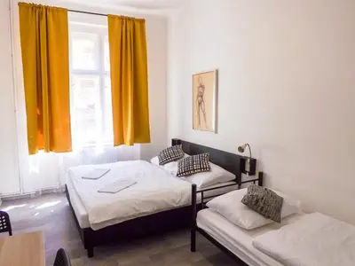 a room with two beds and a window with yellow curtains at Spacious room E1 in centre of Prague in Prague