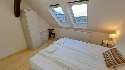 a bedroom with a white bed and two windows at Prague Panorama Loft in Prague