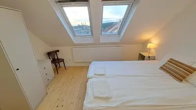 a bedroom with a large white bed with two windows at Prague Panorama Loft in Prague