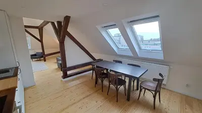 a dining room with a table and chairs and two windows at Prague Panorama Loft in Prague