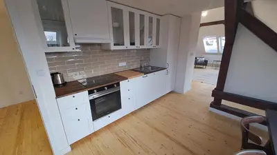 a kitchen with white cabinets and a wooden floor at Prague Panorama Loft in Prague