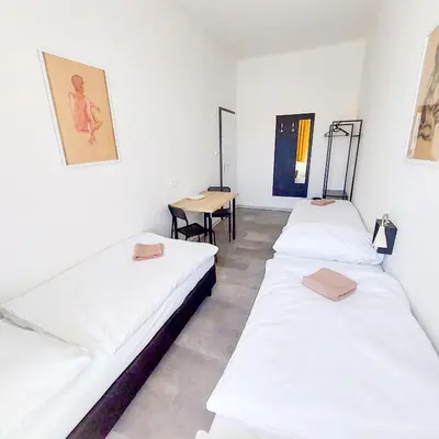three beds in a room with a table at Practical room near the main station H3 in Prague