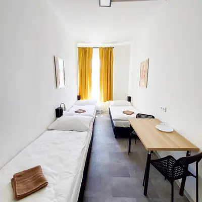 a room with two beds and a wooden table at Practical room near the main station H3 in Prague