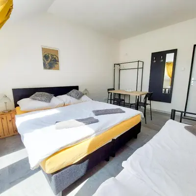 two beds in a room with a table and a mirror at Beautiful attic room R3 in Prague