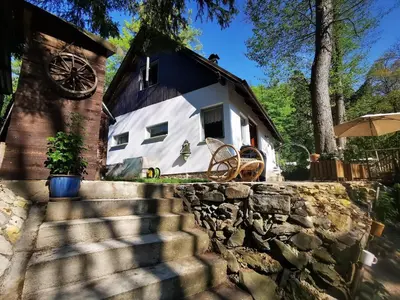 a white house with a black roof and a stone wall at fairy tale cottage on water stream, 30 minutes from South Prague in Davle