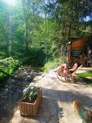 a person sitting in a chair next to a stream at fairy tale cottage on water stream, 30 minutes from South Prague in Davle