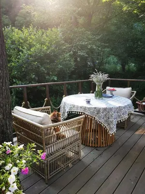 a table and chairs with a cat sitting on a deck at fairy tale cottage on water stream, 30 minutes from South Prague in Davle