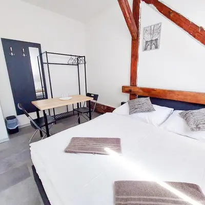 a bedroom with a large white bed and a table at Útulný podkrovní pokoj R4 v Praze in Prague