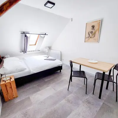 a bedroom with a bed and a table with chairs at Romantický pokojíček v podkroví R5 in Prague