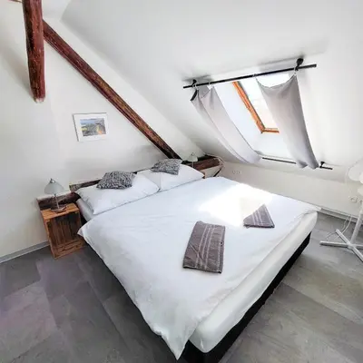 two beds in a bedroom with a large window at Romantický pokojíček v podkroví R5 in Prague