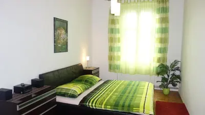 a bedroom with a bed with green sheets and a window at Apartments Rokytka - Praha in Prague