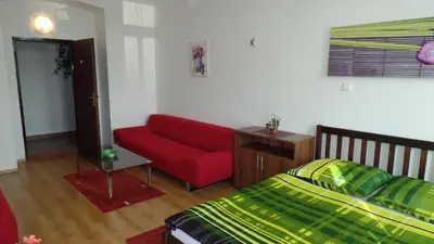 a bedroom with a red couch and a bed at Apartments Rokytka - Praha in Prague