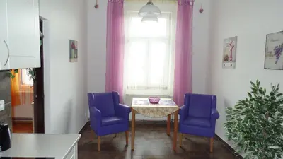 a dining room table with two blue chairs and a window at Apartments Rokytka - Praha in Prague