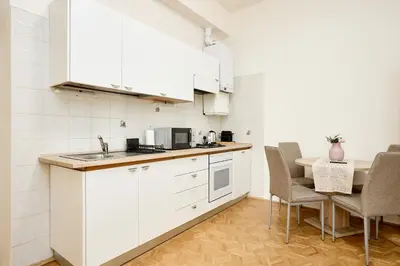 a kitchen with white cabinets and a table and chairs at Alma Apartments in Prague