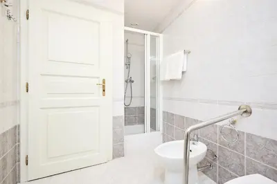 a white bathroom with a shower and a toilet at Alma Apartments in Prague