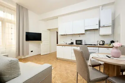a kitchen with white cabinets and a table with chairs at Alma Apartments in Prague