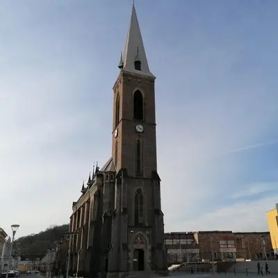 a church with a tall tower with a clock on it at Garden house on the Vltava riverbank 15 min to Prague in Kralupy nad Vltavou