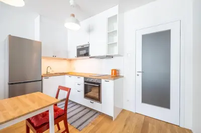 a kitchen with white cabinets and a wooden table and chairs at Peaceful and cosy newly built studio with parking in Prague