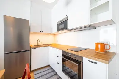 a kitchen with white cabinets and a stainless steel refrigerator at Peaceful and cosy newly built studio with parking in Prague