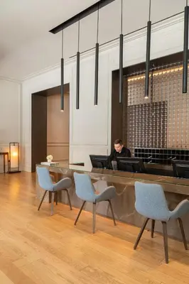 a man sitting at a desk in a lobby with chairs at BoHo Prague Hotel - Small Luxury Hotels in Prague