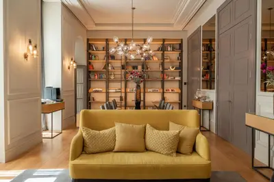 a living room with a yellow couch in front of a book shelf at BoHo Prague Hotel - Small Luxury Hotels in Prague