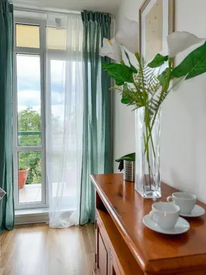 a vase of flowers on a wooden table with a window at Sunny Flat with Terrace & Park View Near City Centre in Prague
