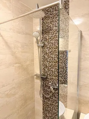 a shower in a bathroom with a glass door at Sunny Flat with Terrace & Park View Near City Centre in Prague