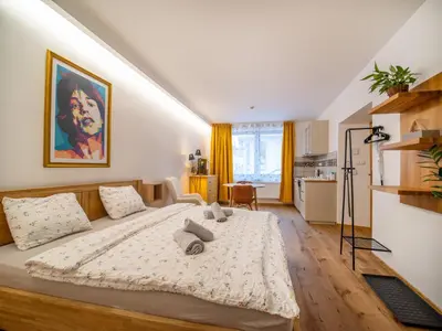 a bedroom with a large bed and a kitchen at Apartmán Mick Jagger in Nymburk
