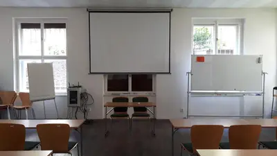 a classroom with tables and chairs and a white screen at Hotel Marianeum in Prague