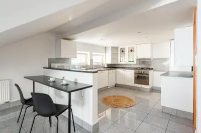 a kitchen with white cabinets and a black table and chairs at Apartment with terrace in Prague Center in Prague