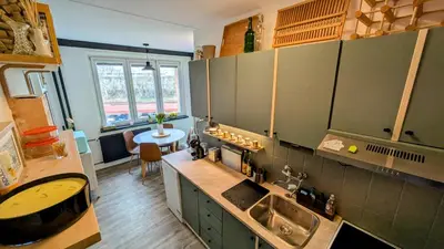 a kitchen with green cabinets and a sink and a table at Stylish Prague 6 Apartment with balcony in Prague