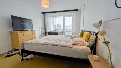 a bedroom with a bed and a tv and a window at Stylish Prague 6 Apartment with balcony in Prague