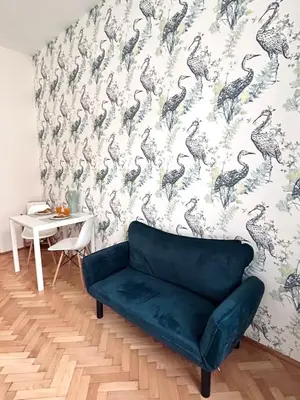 a living room with a blue couch and a bird wallpaper at Studio Oliver in Prague