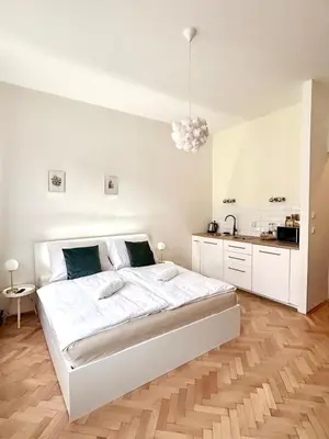 a white bedroom with a large bed and a kitchen at Studio Oliver in Prague