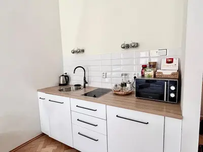 a kitchen with white cabinets and a black microwave at Studio Oliver in Prague