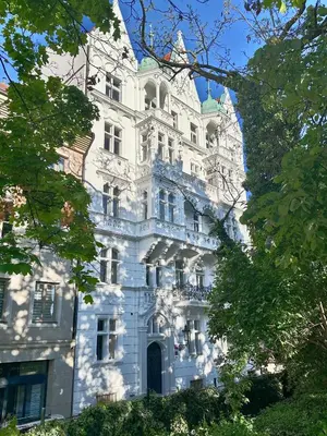 a white building with trees in front of it at Apartment Divadelni - Historic Center & steps from Charles Bridge in Prague