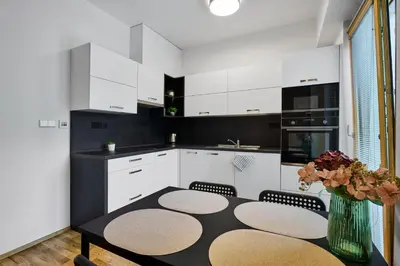 a kitchen with white cabinets and a table with chairs at Residence Kobrova with free parking in Prague