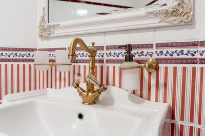 a bathroom with a white sink and a gold faucet at Penzion Ztracený mlýn in Slapy