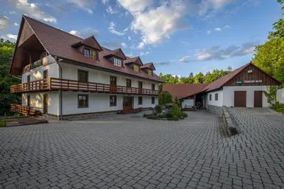 a large white building with a brick courtyard at Penzion Ztracený mlýn in Slapy