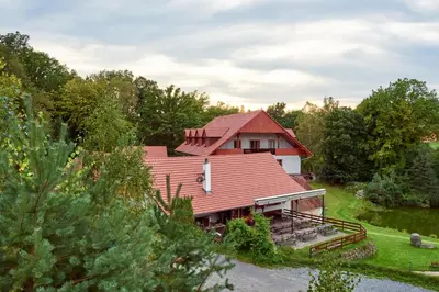 a house with a red roof on a field at Penzion Ztracený mlýn in Slapy