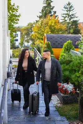a man and woman walking down a sidewalk with luggage at Wellness & SPA boutique Hotel pod lipkami Prague in Prague