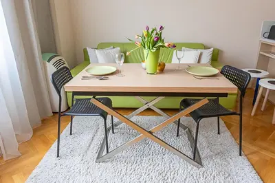 a dining room table with chairs and a green couch at Sunny apartment in Prague
