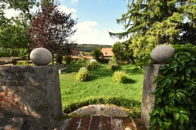 a garden with a stone fence in the grass at Apartment at Château Domoušice in Domoušíce