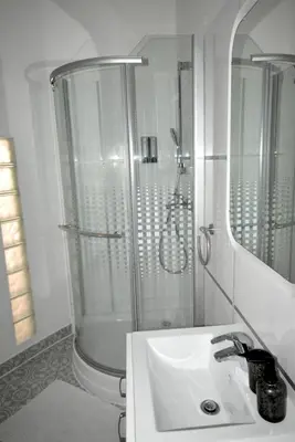 a white bathroom with a shower and a sink at City center apartment in Prague