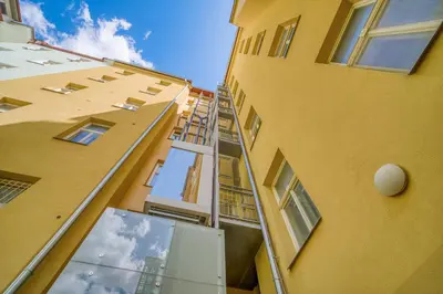 a tall yellow building with a fire ladder on it at Botanical Escape Apartment in Prague