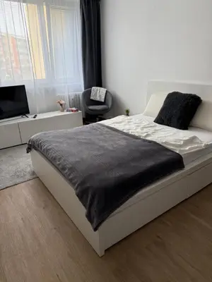 a white bed with a black blanket on it in a bedroom at City view Apartment Lenka in Prague