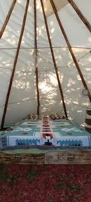 a bed in a tent with the sun in the background at Tee-pee u Honzíka in Zbečno